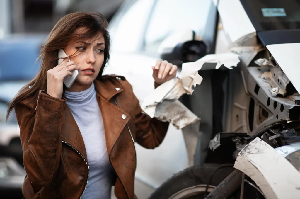 young woman in despair crying next to her wrecked car