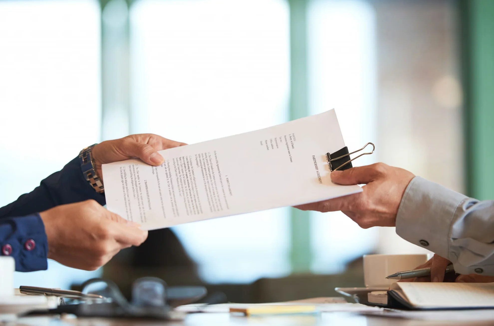 loseup of hands passing the contract to unrecognizable businessman