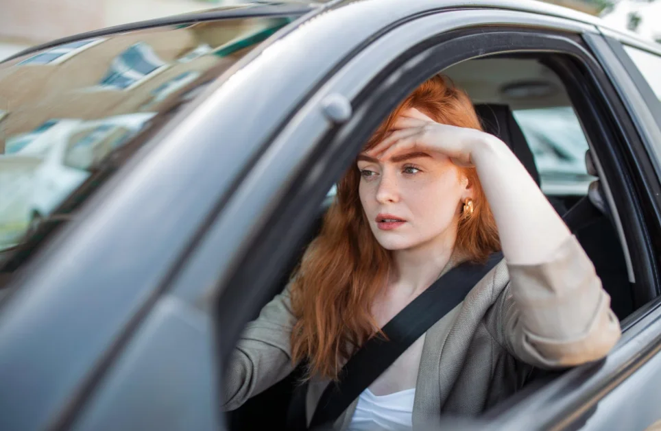 nervous female driver sits at wheel has worried expression