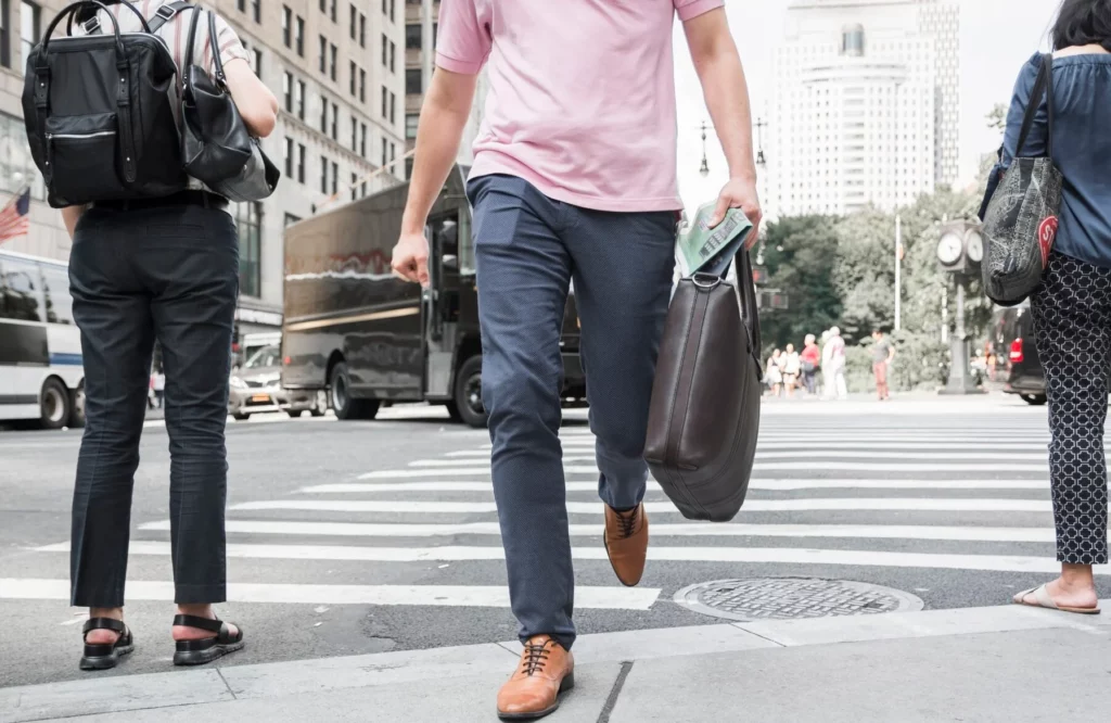 crop man with bag crossing road